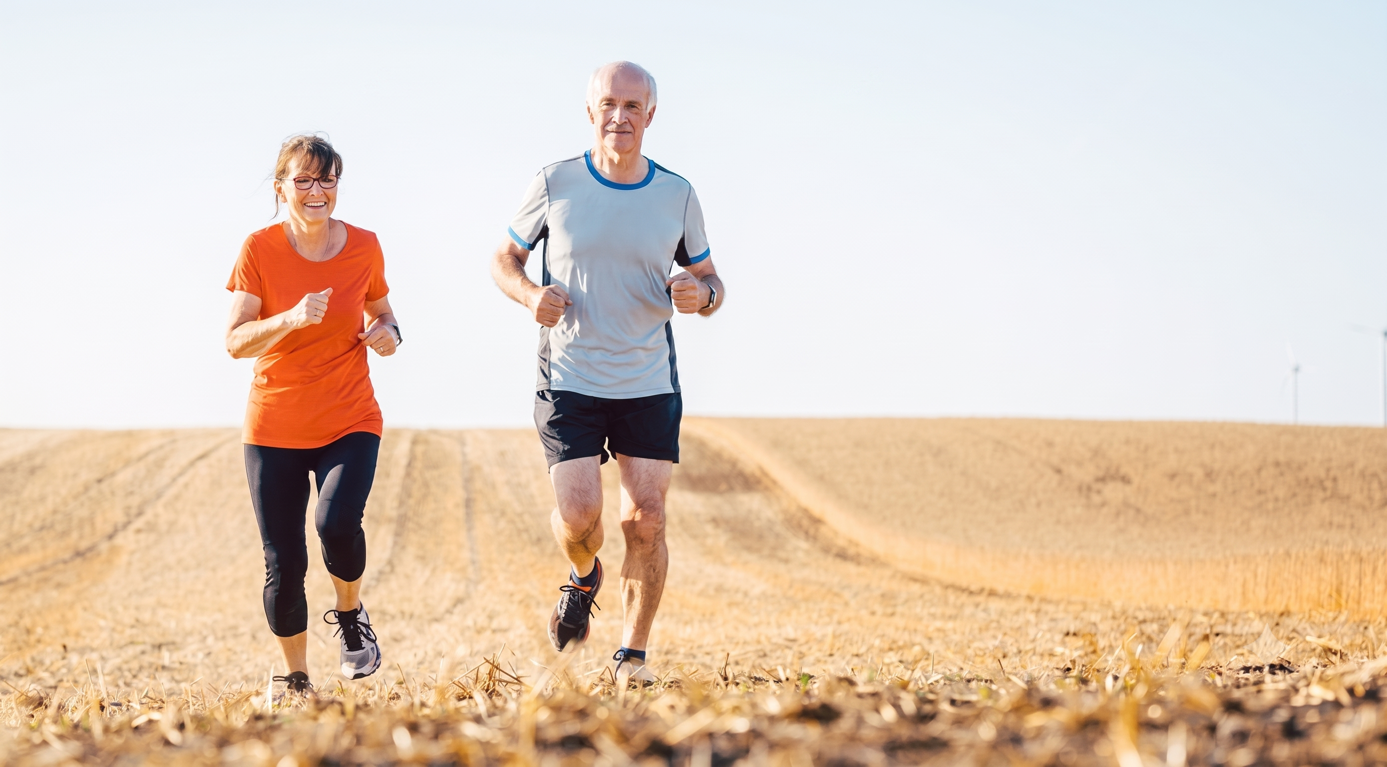 Active older couple happily jogging outdoors